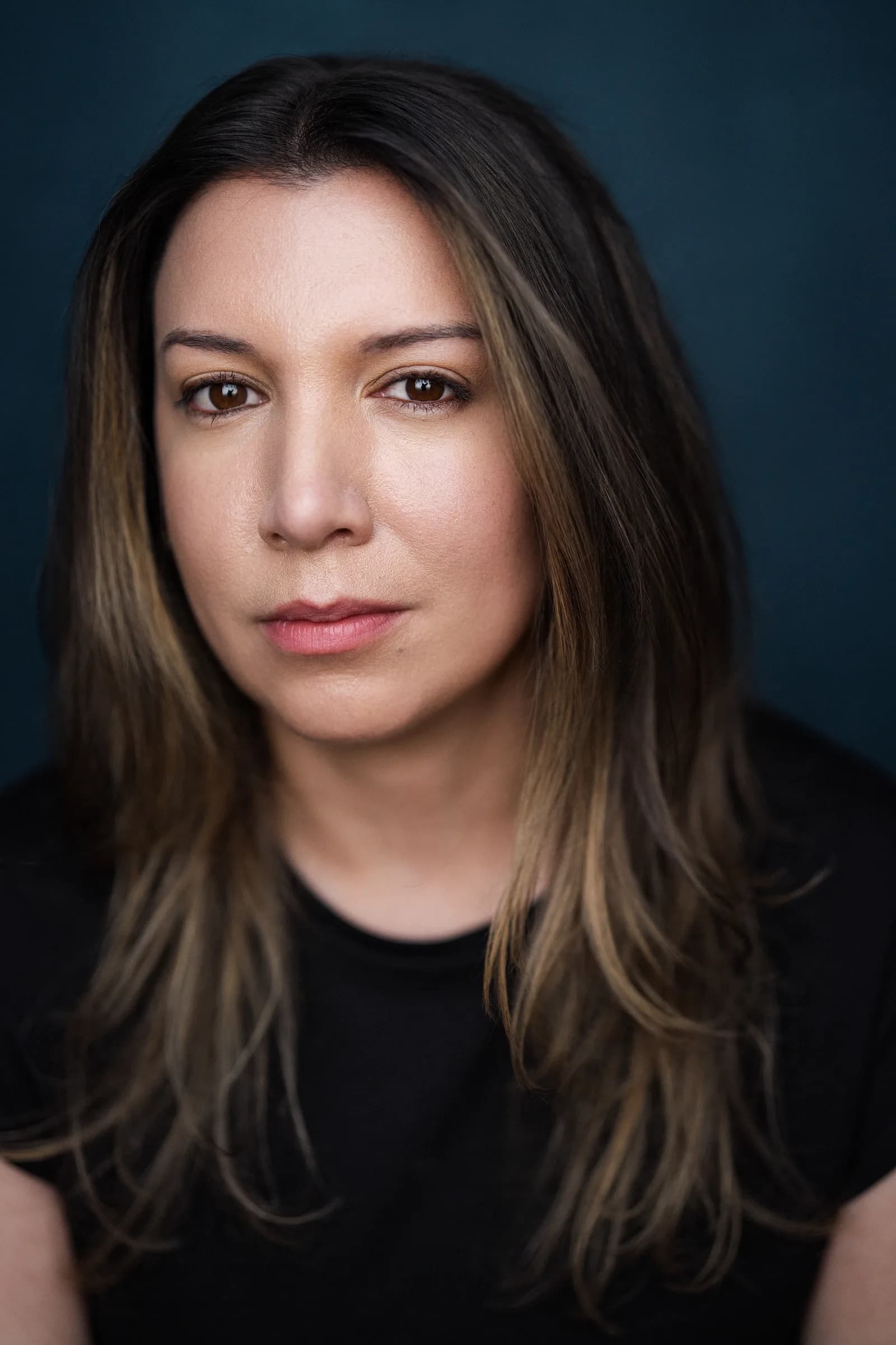 DeAnna Powell, dramatic headshot on a dark teal backdrop